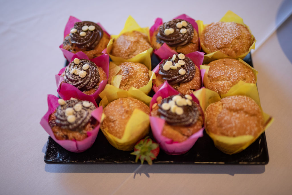 Assorted Hotel Cupcake Display Delicious cupcakes topped with chocolate, served on a tray with colourful wrappers, offering a sweet treat at the hotel buffet.